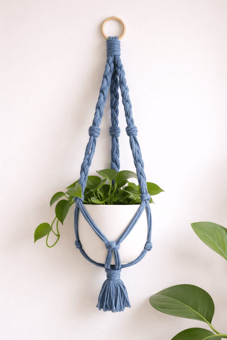 Braided denim plant hanger DIY made from old jeans, featuring knotted cradle design holding a white planter with indoor plant