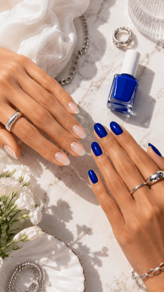 Cobalt Blue Nail Trend: Glossy, bold blue nails pop beside nude-pink on marble with chic jewelry&mdash;perfect for modern style. Save this idea so you can come back to it later.