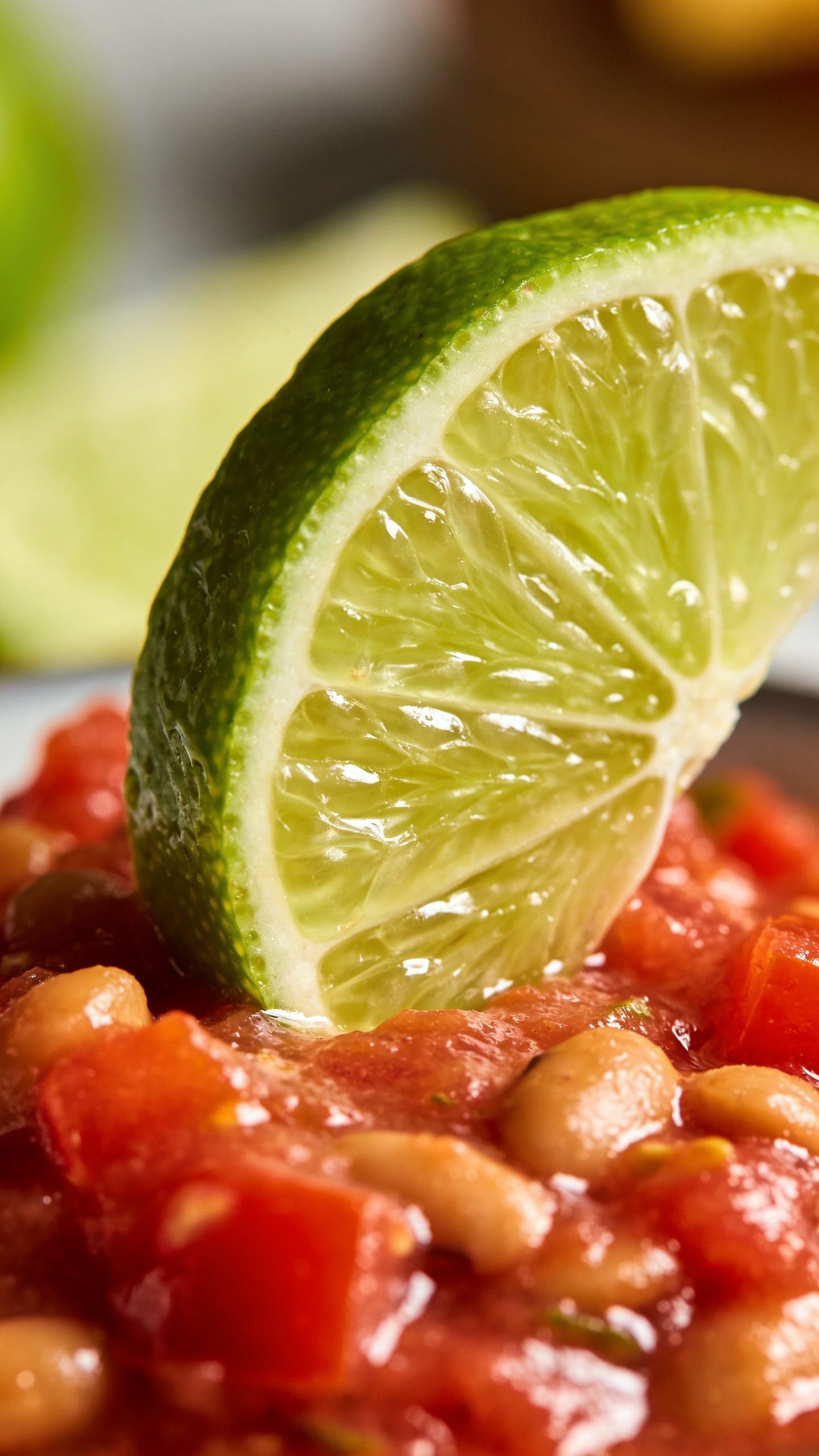 closeup of lime wedge over bright tomato-bean dip